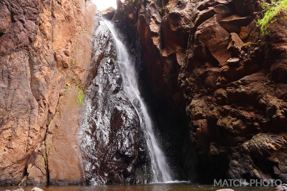 Wasserfall an einer Felswand. Nasser Stein glänzt und schimmert.